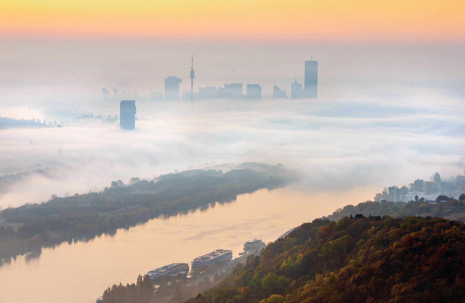 Blick vom Leopoldsberg im Morgenlicht: Die Donau führt in den Nebel, aus dem nur die Hochhäuser der Donaucity und der Donauturm ragen.